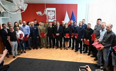 Uczestnicy spotkania stoją razem pozując do pamiątkowego zdjęcia. Wśród nich są wyróżnieni, rodziny i ich przełożeni.