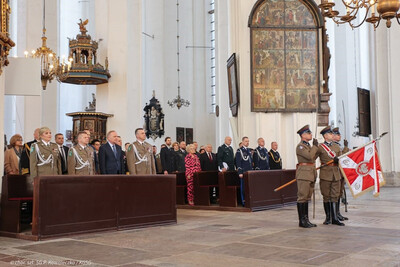 bazylika mariacka w gdańsku uczestnicy mszy z okazji rocznicy powołania sg stoją  w ławkach, przed nimi poczet sztandarowy złożony z 3 funkcjonariuszy sg