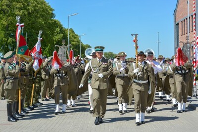 Orkiestra Reprezentacyjna SG podczas przemarszu. na czele orkiestry idzie jej Naczelnik, obok niego Tamburmajor orkiestry trzymający w dłoni ciupagę zamiast buławy. z lewej strony stoją poczty sztandarowe zebrane podczas uroczystości.
