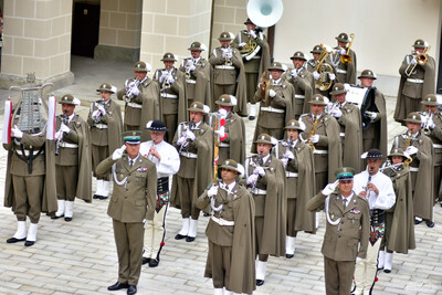 Orkiestra Reprezentacyjna straży granicznej stoi w szyku podczas uroczystości. przed nią stoją odpowiednio po lewej stronie naczelnik orkiestry, następnie tamburmajor orkiestry i po prawej zastępca naczelnika orkiestry. wszyscy trzej oddają honor i stoją na baczność.