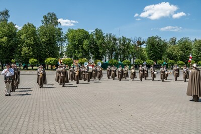 orkiestra reprezentacyjna straży granicznej wykonuje pokaz musztry paradnej. przed nią stoi jej tamburmajor trzymając w dłoni ciupagę zamiast buławy.