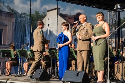soliści orkiestry reprezentacyjnej straży granicznej wykonują utwór.  w tle znajdują się muzycy orkiestry którzy koncert wykonują na siedząco. orkiestrą dyryguje jej naczelnik.