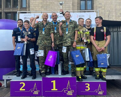 Umundurowani funkcjonariusze SG (1 miejsce), Policji (2 miejsce) i PSP (3 miejsce) stoją na podium. Trzymają w rękach puchary, medale i dyplomy.