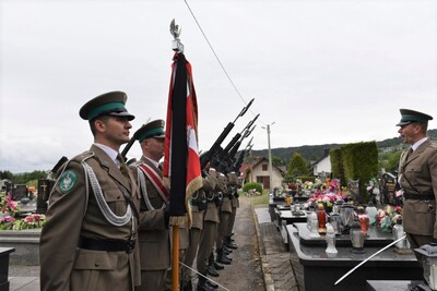 na pierwszym planie widać funkcjonariusza straży granicznej, który jest w poczcie sztandarowym, następnie widoczny jest sztandar karpackiego oddziału straży granicznej. nieco dalej kompania reprezentacyjna oddaje salwę honorową.