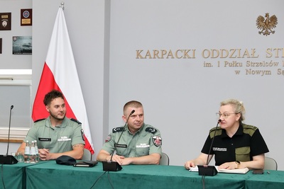 dwóch celników i zastępca komendanta kaosg - płk sg renata obrzut siedzą przy stole prezydialnym. Zastępca komendanta kaosg mówi do mikrofonu