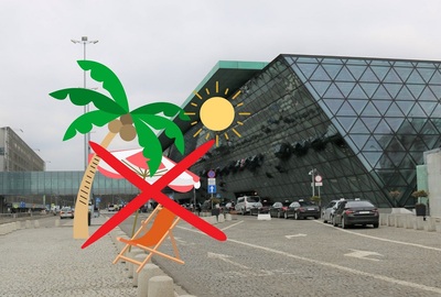 Na tle budynku kraków airpoprt umieszczono grafikę palmę i leżak przekreślone czerwonym iksem