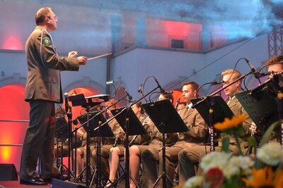 Dyrygent stoi przed kilkoma muzykami orkiestry i dyryguje