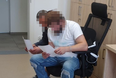 Dwaj zatrzymani Gruzini z zapikselizowanymi twarzami  siedzą na stołkach. W rękach trzymają  papiery do zapoznania.