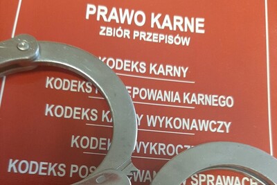 kajdanki koloru srebrnego ułożone na spisie prawa karnego.