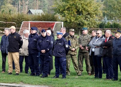 Obserwatorzy manewrów stoją na trawniku. za nimi ołtarz papieski w starym sączu