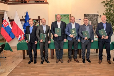 Pełnomocnicy graniczni RP i RS po podpisaniu protokołu ustawili się do pamiątkowego zdjęcia. w rękach trzymają teczki w których są podpisane protokoły ze spotkania