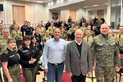 na zdjęciu widoczny od prawej komendanta karpackiego oddziału straży granicznej, następnie dyrygent jubilat Bolesław żulia, obok niego dyrygent orkiestry reprezentacyjnej straży granicznej. za nimi stoją muzycy orkiestry reprezentacyjnej straży granicznej. całość odbywa się w sali prób orkiestry. zdjęcie wykonane podczas próby.