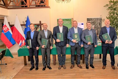 Pełnomocnicy graniczni RP i RS po podpisaniu protokołów ustawili się do pamiątkowego zdjęcia. Stoją a w rękach trzymają podpisane protokoły ze spotkania.