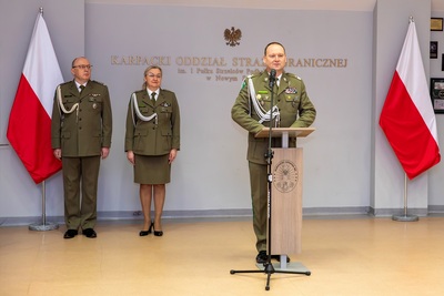 komendant kaosg przemawia na mównicy za nim stoją jego zastępcy
