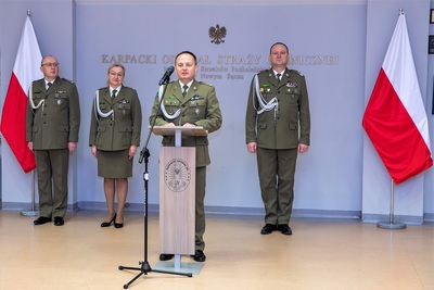 sala odpraw. komendant placówki sg w krakowie balicach przemawia do uczestników uroczystości. za nim stoi komendant kaosg i jego zastępcy