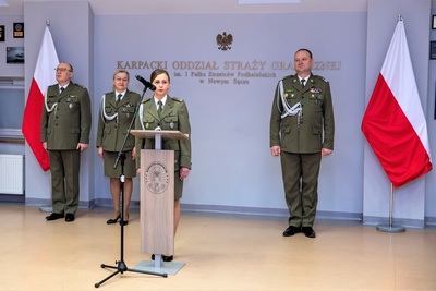 sala odpraw. odchodząca na emeryturę funkcjonariuszka przemawia do uczestników uroczystości. za nią stoi komendant kaosg i jego zastępcy