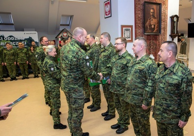 Komendant karpackiego oddziału w asyście swojego zastępcy oraz naczelnika orkiestry reprezentacyjnej straży granicznej wręcza mianowania na wyższe stanowiska służbowe funkcjonariuszom straży granicznej. całość odbywa się w sali odpraw oddziału.