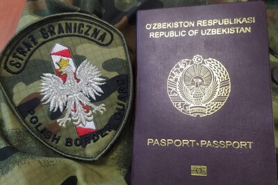 Paszport Uzbekistanu w kolorze bordowym ze złotymi napisami ułożonym obok emblematu Straży granicznej. emblemat posiada napis straż graniczna pod napisem znajduje się godło polski w postaci orła biało]ego oraz symbol słupka granicznego. pod nim napis w języku angielskim polish border guard.