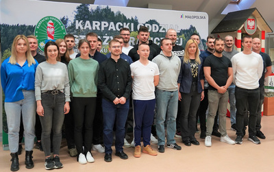 nowo przyjęci funkcjonariusze pozują do zdjęcia na tle banneru z napisem karpacki Oddział Straży granicznej i widocznym logo oddziału. zdjęcie robione jest w sali odpraw i tradycji oddziału