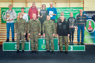 trzy zwycięskie drużyny stoją na podium. przed nimi wręczający medale i puchary przedstawiciele  KGSG oraz OSSG w Lubaniu