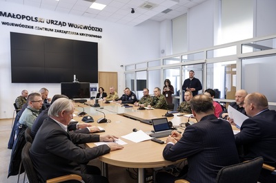 przedstawiciele służb odpowiedzialnych za bezpieczeństwo siedzą przy stole wraz z wojewoda małopolskim.