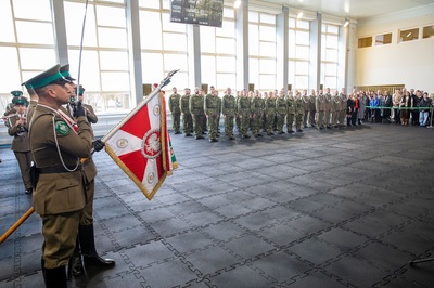 hala sportowa. na pierwszym planie sztandar kaosg.  dalej nowo przyjęci oraz mianowani funkcjonariusze i pracownicy cywilni a także rodziny przyjętych do służby. wszyscy stoją na baczność