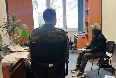 Zatrzymany obywatel Nigerii siedzi na krześle w pomieszczeniach biurowych placówki sg w krakowie. Przed nim siedzi funkcjonariusz sg