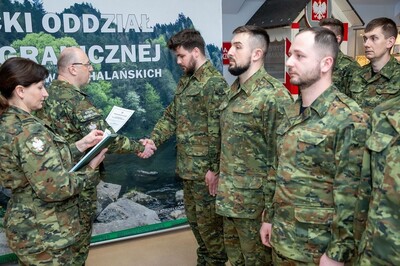 trzech funkcjonariuszy mianowanych na stopień kaprala stoi na baczność. płk marcisz wręcza jednemu z nich akt mianowania na stopień