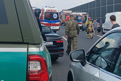 na zdjęciu widoczne jest zdarzenie drogowe. wypadek ma miejsce na autostradzie. na pierwszym planie widoczny pojazd służbowy straży granicznej. w tle widoczne są samochody biorące udział w kolizji.