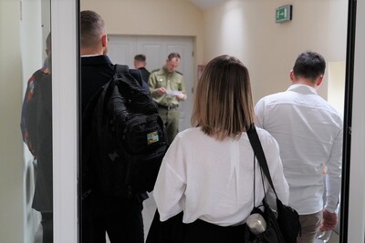 na pierwszym planie widoczni kandydaci starający się do przyjęcia do służby w straży granicznej. w tle widoczny funkcjonariusz straży granicznej sprawdzający obecność.