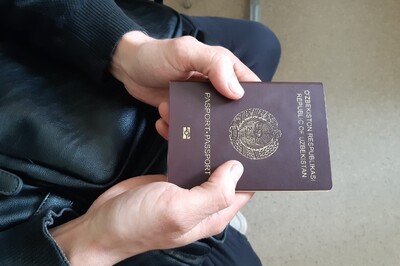 zatrzymany cudzoziemiec - obywatel uzbekistanu - w rękach trzyma swój paszport. Zbliżenie na ręce.