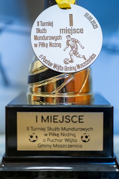 na zdjęciu widać medal za zajęcie pierwszego miejsca oraz plakietke przyklejona do pucharu z napisami 1 miejsce II turniej służb mundurowych w piłkę nożną o puchar wójta gminy moszczenica