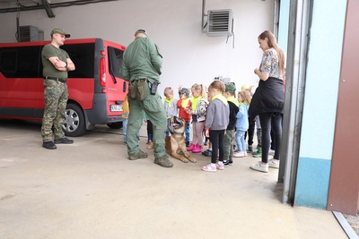dzieci patrzą na psa służbowego który wykonuje komendy przewodnika psa