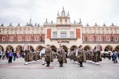 Orkiestra reprezentacyjna przed występem na tle sukiennic w Krakowie po obu stronach ludzie patrzący na orkiestrę