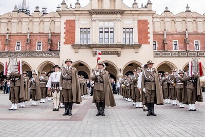 Muzycy orkiestry stoją na płycie krakowskiego rynku. w tle sukiennice
