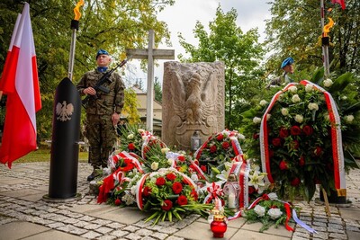 Na placu stoi kamienny pomnik z płaskorzeźbą dużego orła w koronie. U jego podstawy ułożono liczne wieńce z czerwonych i białych kwiatów, ozdobione biało-czerwonymi wstęgami z napisami. Obok pomnika stoją na warcie dwaj żołnierze w mundurach polowych, w błękitnych beretach, z karabinami w rękach. Z lewej strony powiewa polska flaga na maszcie. Obok ustawiono czarny znicz w kształcie pocisku artyleryjskiego z wizerunkiem orła.