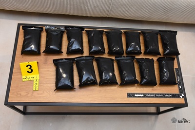 Na zdjęciu widać brązowy stół na którym poukładane są czarne woreczki.