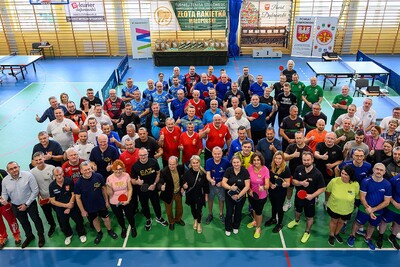 Na zdjęciu widać dużą grupę ludzi ubranych w sportowe ciuchy. Wszyscy stoją na hali sportowej i pozują do zdjęcia.