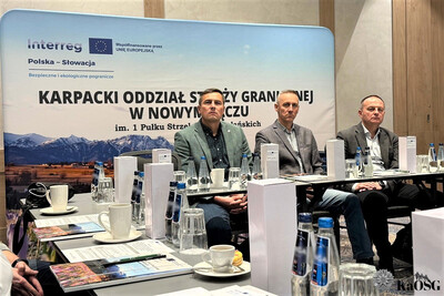 uczestnicy spotkania - trzy osoby - siedzą przy stole . słuchają prelegenta.