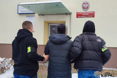 zatrzymany cudzoziemiec prowadzony jest przez dwóch funkcjonariuszy w stroju cywilnym z opaskami na ramieniu z napisem straż graniczna