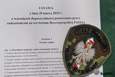 Na zdjęciu widać białą kartkę papieru, na której czarnymi literami napisany jest tekst ustawy. Dodatkowo po prawej stronie widać emblemat Straży Granicznej.