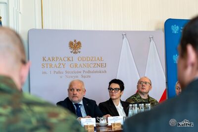 Ekran monitora z napisem: „Odprawa roczna Karpackiego Oddziału Straży Granicznej im. 1 Pułku Strzelców Podhalańskich za 2025 rok. Kraków, 26 lutego 2026 r.”. Na ekranie widać logotyp oddziału oraz zdjęcie Tatr.