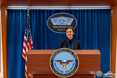 Kobieta stoi przy mównicy w departamencie stanu stanów zjednoczonych w tle po prawej stronie flaga usa na mównicy logotyp departamentu