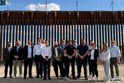 kilkanaście osób uczestników szkolenia stoi na tle bariery na granicy usa i meksyku