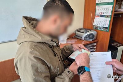 Na zdjęciu mężczyzna trzymający w rękach dokumenty prawdopodobnie paszport i decyzję administracyjną. w Tle pomieszczania biurowe.