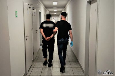 jeden z zatrzymanych cudzoziemców jest prowadzony przez nieumundurowanego funkcjonariusza korytarzem placówki sg w krakowie-balicach