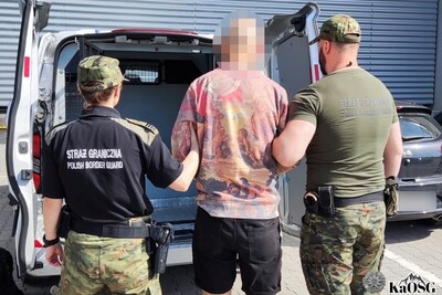 jeden z ujawnionych polaków jest prowadzony przez dwoje funkcjonariuszy sg