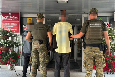 Przed wejściem do urzędu stoją cztery osoby. Dwie z nich to funkcjonariusze Straży Granicznej - doprowadzają osoby zatrzymane