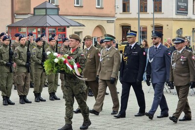Przedstawiciele służb mundurowych składają wieniec podczas uroczystości.
